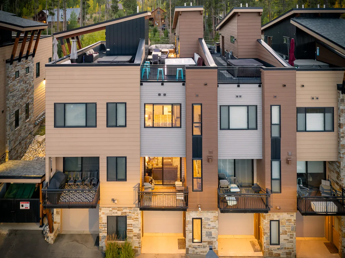 A cozy rooftop terrace with balconies featuring seating, illuminated windows, and a welcoming outdoor dining area. The inviting ambiance suggests group gatherings, stargazing, and shared meals in an elevated setting.