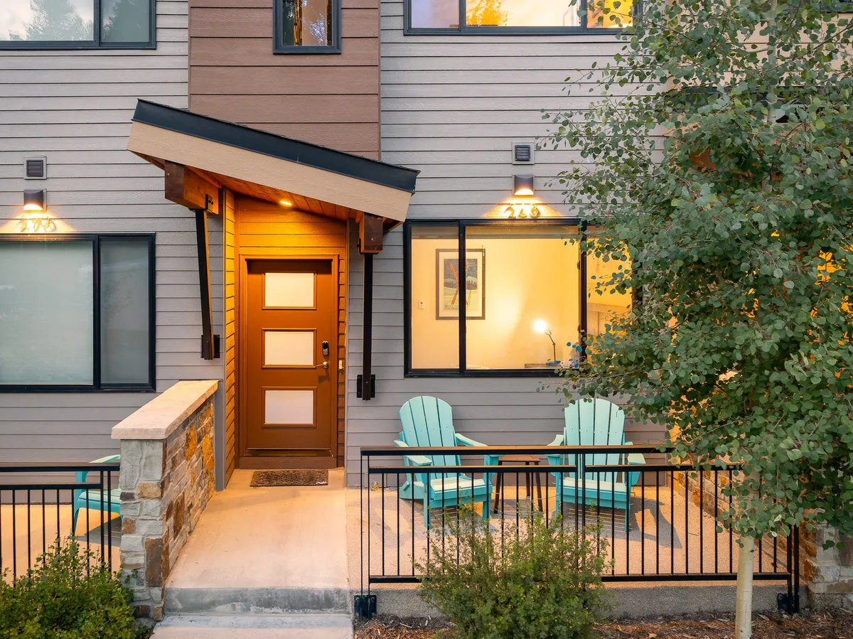 A cozy exterior view of the villa's front door, accented by blue chairs and stone walls. The porch area suggests a welcoming entrance and a spot to enjoy fresh air at any time of day.
